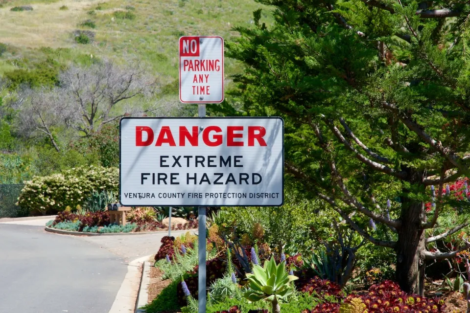"Danger Extreme Fire Hazard" sign on street sign post below "No Parking" sign.